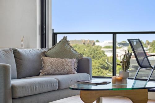 a living room with a couch and a glass table at Oleria - Serene Bohem Retreat in Adelaide
