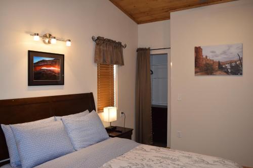 1 dormitorio con cama, lámpara y ventana en Log Cottages at Bryce Canyon #2 en Cannonville