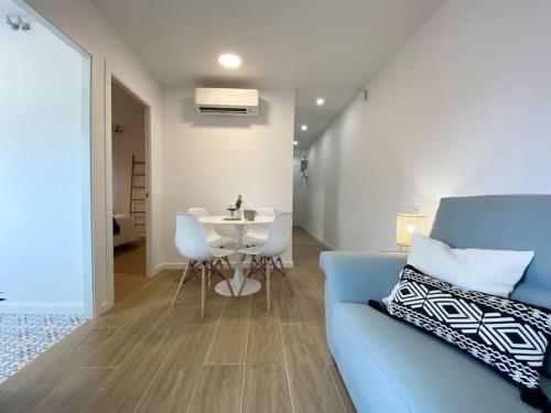 ein Wohnzimmer mit einem blauen Sofa und einem Tisch in der Unterkunft ´WALK TO CAMP NOU´ STYLISH 3BD SMART TV Wifi in Hospitalet de Llobregat