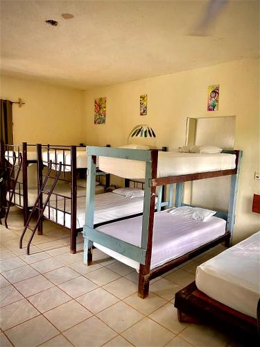 a room with three bunk beds and a mirror at Hostalito Lahar in Bacalar