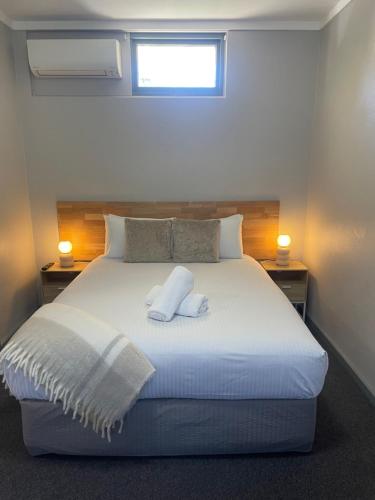 a bedroom with a white bed with two pillows at Lismore Fair Dinkum Motel in Lismore