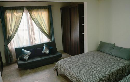 a bedroom with a bed and a couch and a window at Los Ríos in Pereira