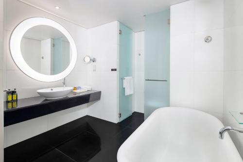 a white bathroom with a sink and a mirror at Nina Hotel Tsuen Wan West in Hong Kong