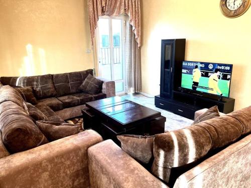 a living room with two couches and a television at Cozy 3 Bedroom Apartment Near 7th Circle in Amman