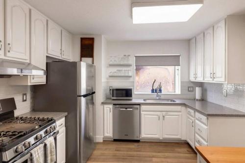 a kitchen with white cabinets and a stainless steel refrigerator at Pacifica Storybook Beach House in Pacifica