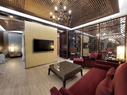 a living room with a couch and a tv at Elysees Motel in Toufen