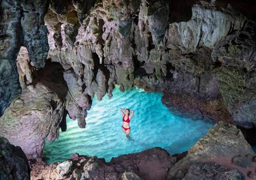 une personne debout dans l'eau dans une grotte dans l'établissement Swell Lodge, à Flying Fish Cove