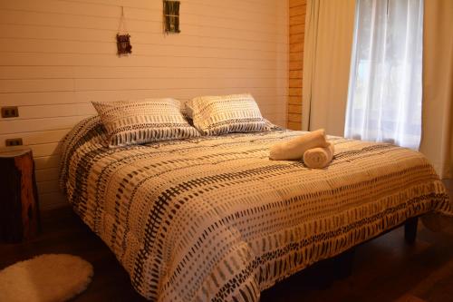 a bed in a bedroom with a blanket and pillows at Ruca del Fuy in Panguipulli