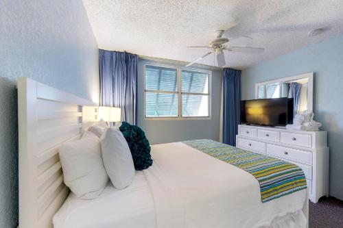 Un dormitorio con una cama blanca y un televisor. en Sunrise Suites - Martinique Suite 108, en Key West