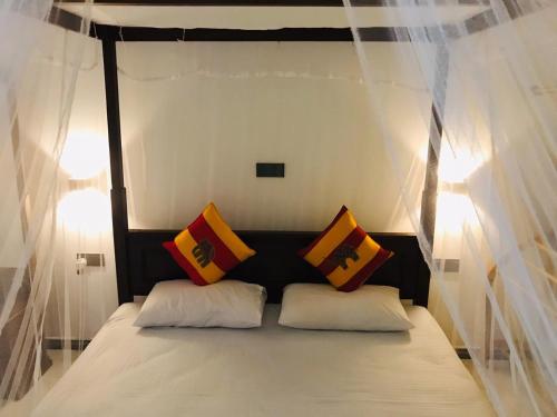 a bedroom with a canopy bed with white and yellow pillows at LSC Villa in Weligama