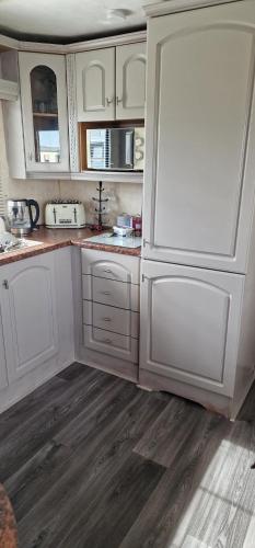 a kitchen with white cabinets and a white refrigerator at H&B Caravan on Marine Holiday Park in Rhyl
