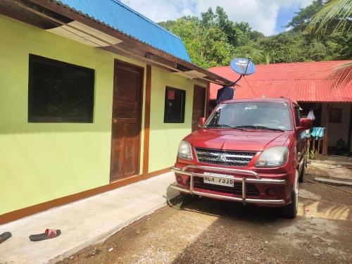 une voiture rouge garée devant une maison dans l'établissement Hondelz Budget Homestay, à Busuanga