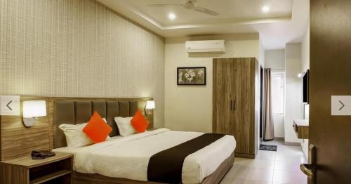 a bedroom with a large bed with orange pillows at Hotel Sindhura Grand in Hyderabad