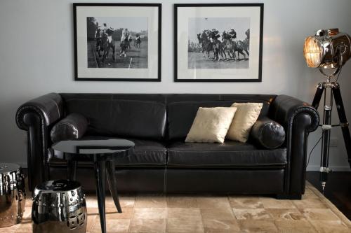 un sofá de cuero negro en una sala de estar con fotografías en Argentario Golf & Wellness Resort, en Porto Ercole