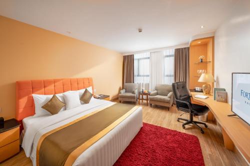 ein Hotelzimmer mit einem großen Bett und einem Schreibtisch in der Unterkunft Fortuna Hotel Hanoi in Hanoi