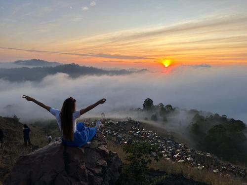 a woman sitting on top of a mountain with her arms outstretched at The Lava Bali Villa and Hot Spring in Kintamani