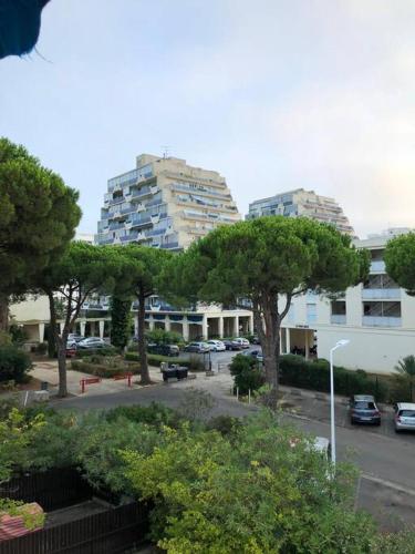 - une vue sur un parking avec des arbres et des bâtiments dans l'établissement studio parking privé climatisation plage proche, à La Grande Motte