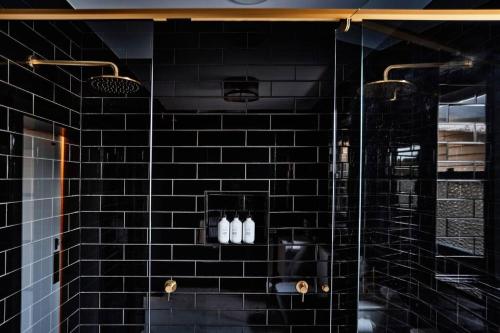 a black tiled shower with three bottles on a shelf at Ruby by Whiskey June in Maryborough