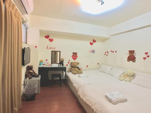 two teddy bears sitting on a bed in a room at Love Feng Jia Apartment Hotel in Taichung