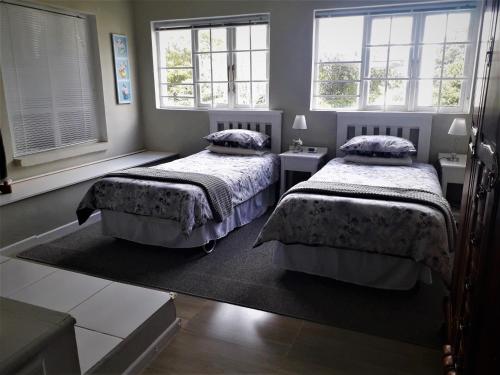 dwa łóżka w pokoju z dwoma oknami w obiekcie Bellhouse Guesthouse w mieście Somerset East