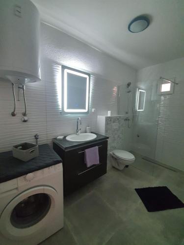 a bathroom with a sink and a washing machine at Apartments Lola in Biograd na Moru
