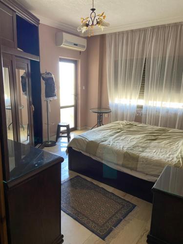 a bedroom with a bed and a dresser and a window at شقة مفروشة للايجار في عمان شارع الجامعة الاردنية in Amman