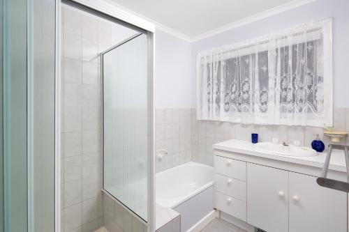 a white bathroom with a shower and a sink at 9 Tunbridge Street in Rhyll