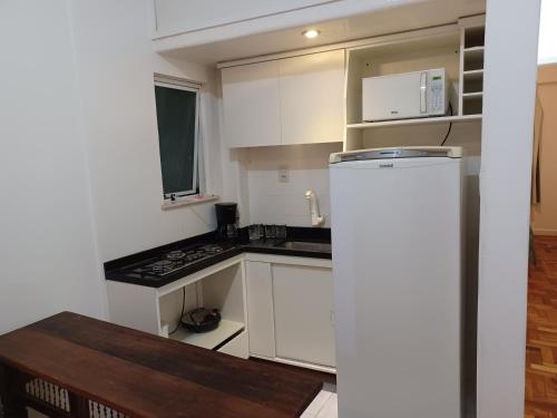 uma pequena cozinha com armários brancos e um frigorífico em Apartamento Jardim Botânico no Rio de Janeiro