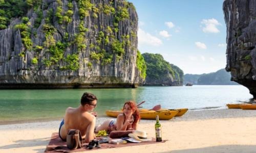 a man and a woman sitting on a beach at Indochine Cruise Lan Ha Bay in Ha Long