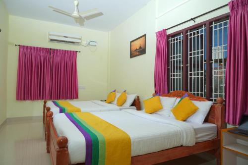 two beds in a room with pink curtains at Umaiyyal Home Stay in Kanyakumari