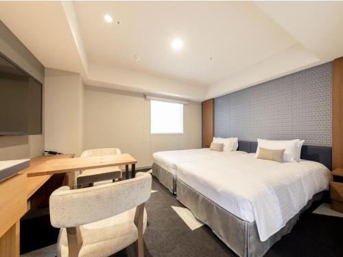 a hotel room with two beds and a desk and a television at Tokyu Stay Sapporo Odori in Sapporo