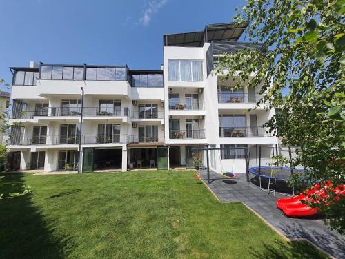 un immeuble d'appartements avec une pelouse devant lui dans l'établissement MIANELLY Apartments Mamaia Nord, à Mamaia Nord – Năvodari