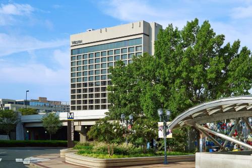 a tall building with a tree in front of it at The Westin Crystal City Reagan National Airport in Arlington