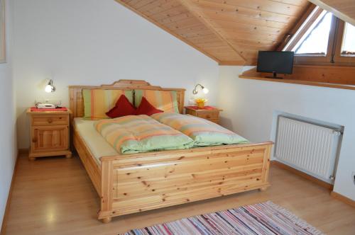 - une chambre avec un lit en bois et une télévision murale dans l'établissement Bacherhof, à Val di Vizze