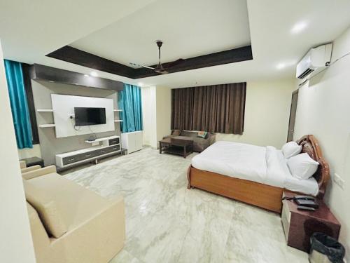 a bedroom with a bed and a couch and a tv at Luxury Home Stay - Lajpat Nagar in New Delhi