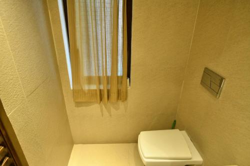 a small bathroom with a toilet and a window at La Closerie - Bay of Bengal in Puducherry
