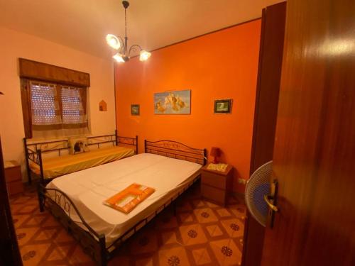 um quarto com paredes cor-de-laranja, uma cama e um lavatório. em Casa alloggio em Scalea