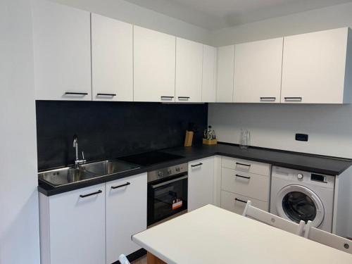 a kitchen with white cabinets and a sink and a dishwasher at Appartamento La Torre in Predazzo