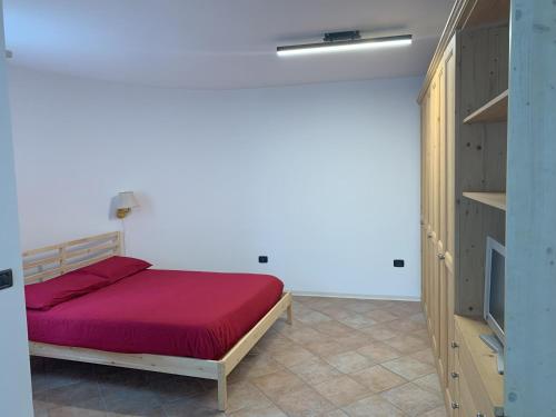 a bedroom with a red bed and a tv at Appartamento La Torre in Predazzo