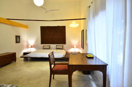 a bedroom with a bed and a desk and a table at La Closerie - Bay of Bengal in Puducherry
