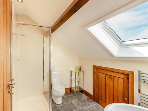 a bathroom with a toilet and a skylight at Warth Barn - Uk44211 in Ingleton