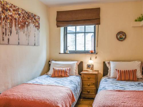two beds in a small room with a window at Stoney End Cottage in Askrigg