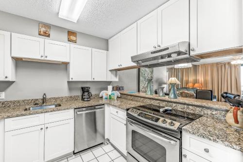a kitchen with white cabinets and a stove top oven at Compass Point 303 in Gulf Shores