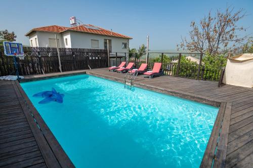 a swimming pool with chairs and a house at וילה בין הר לכנרת in Yavneʼel