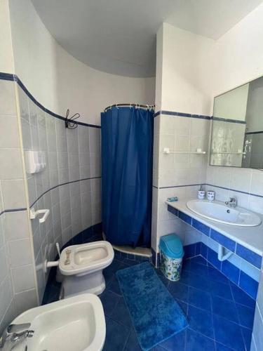 ein Badezimmer mit einem blauen Duschvorhang, einem WC und einem Waschbecken in der Unterkunft Villa Serena in Vibonati