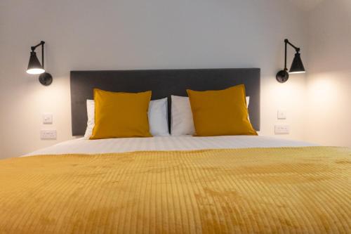 a bedroom with a large bed with two yellow pillows at Combie Lane Apartment in Oban