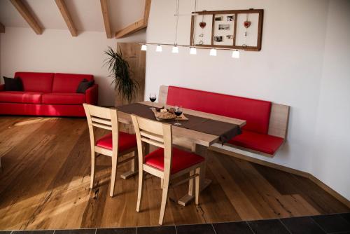 a dining room with a table and red couch at Perchnerhof in Terento