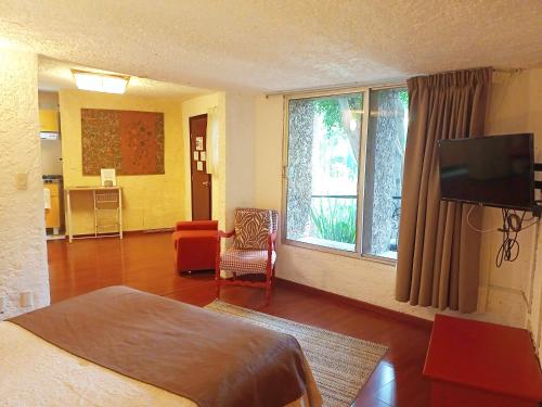 a hotel room with a bed and a tv and a living room at Suite 1-A Monasterio Garden House Welcome to San Angel in Mexico City