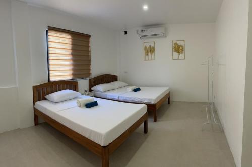 two beds in a room with a window at Kasamigos Guesthouse with Fast Internet in Puerto Princesa City