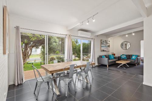 a dining room with a table and chairs and a couch at Ocean Reach Sunset Villa in Cape Woolamai